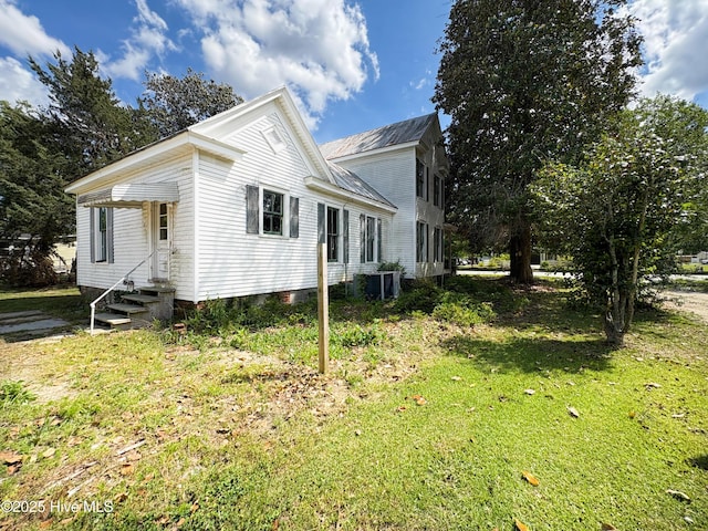 view of side of home with entry steps, central AC unit, a lawn, and metal roof