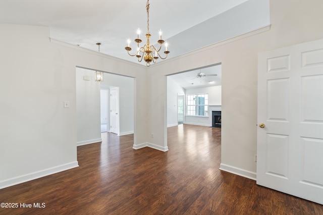 unfurnished dining area featuring baseboards, dark wood finished floors, ceiling fan with notable chandelier, and a fireplace