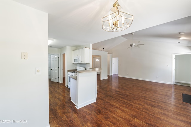 kitchen with ceiling fan with notable chandelier, a peninsula, dark wood-style floors, white appliances, and white cabinetry