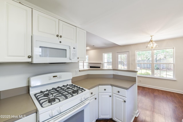 kitchen with dark wood finished floors, white cabinets, a peninsula, a chandelier, and white appliances