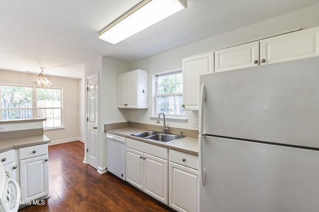 kitchen with white appliances, dark wood-style floors, white cabinetry, a chandelier, and a sink