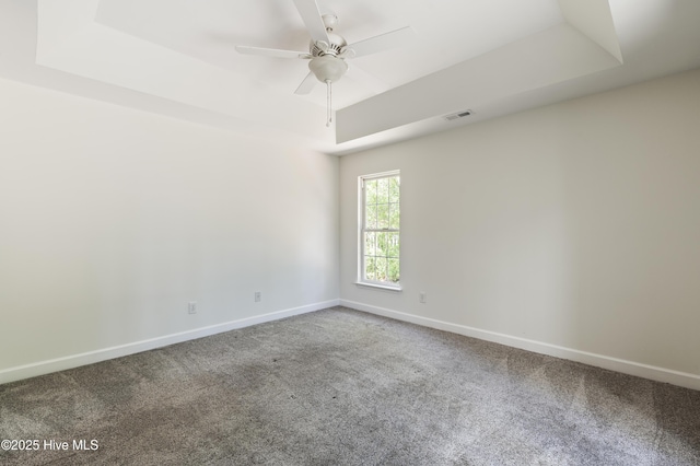 empty room featuring carpet floors, visible vents, and a raised ceiling