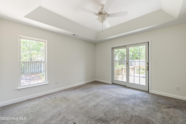 spare room with visible vents, a ceiling fan, carpet, and a tray ceiling