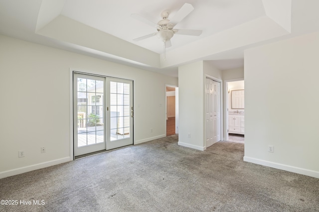 unfurnished room featuring baseboards, carpet, a raised ceiling, and a ceiling fan