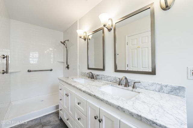 full bath featuring double vanity, a sink, and a tile shower