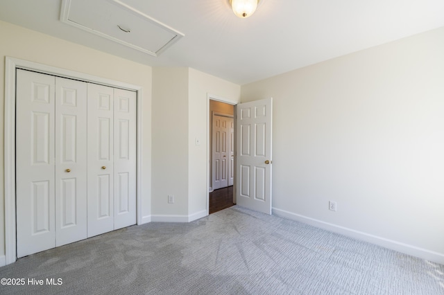 unfurnished bedroom featuring attic access, baseboards, carpet, and a closet