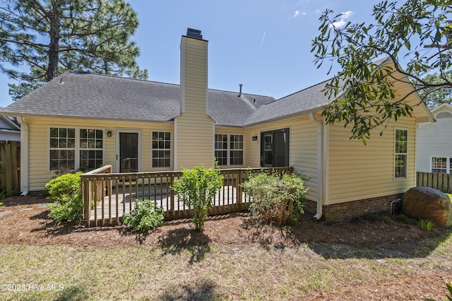 back of property with a deck, fence, a chimney, and a shingled roof
