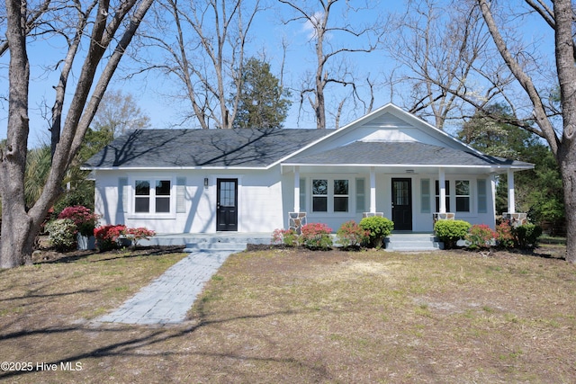 view of front of property with a shingled roof, a front lawn, and covered porch