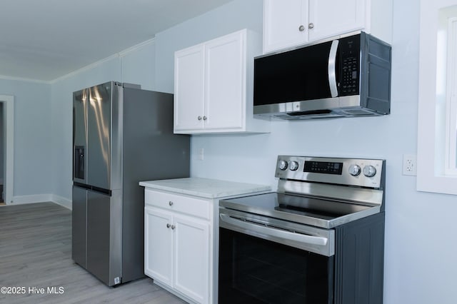 kitchen with light wood-style floors, crown molding, white cabinets, and stainless steel appliances