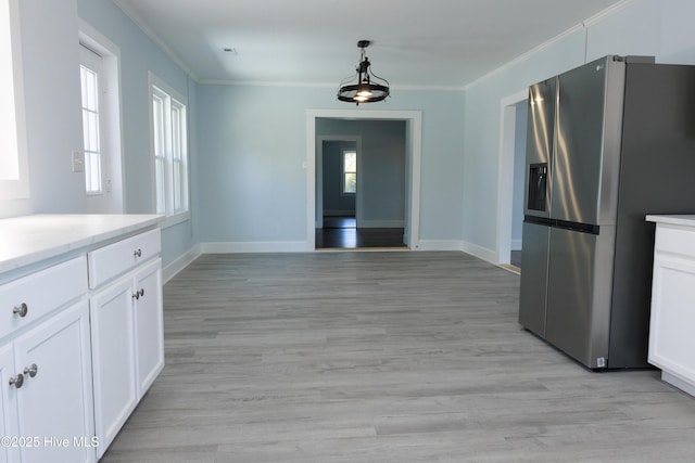 kitchen with white cabinets, baseboards, ornamental molding, and stainless steel fridge with ice dispenser