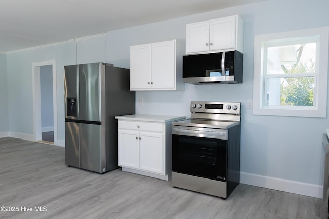 kitchen with appliances with stainless steel finishes, baseboards, light wood-type flooring, and white cabinets