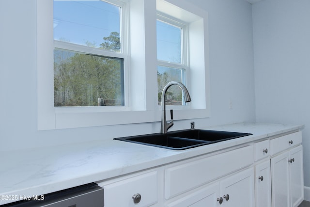 kitchen featuring a sink, white cabinets, light stone countertops, and dishwasher