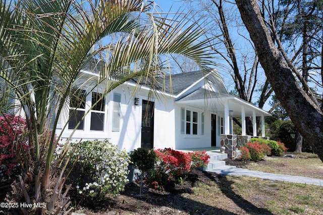 view of front of house with covered porch, a shingled roof, and concrete block siding
