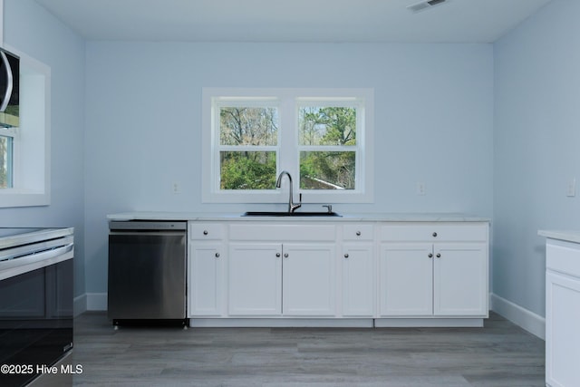 kitchen featuring appliances with stainless steel finishes, light wood-type flooring, a sink, baseboards, and white cabinetry