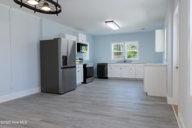 kitchen featuring light wood-type flooring, light countertops, white cabinetry, a sink, and stainless steel appliances