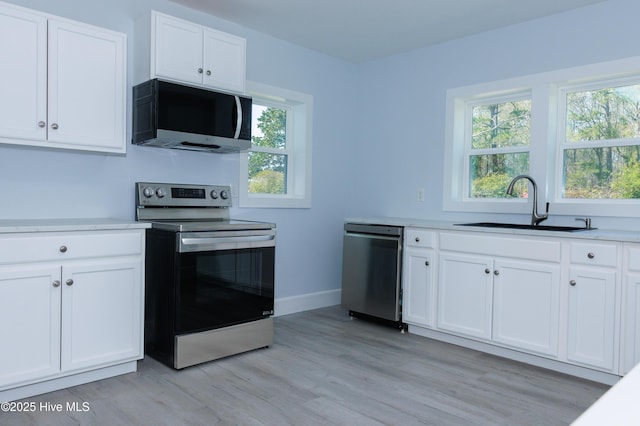 kitchen featuring a sink, light wood-style flooring, appliances with stainless steel finishes, and white cabinets