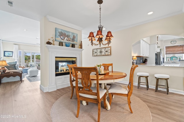 1710 Deerfield Ct SW Unit 4A, Ocean Isle Beach, NC 28469 - dining room with crown molding, arched walkways, recessed lighting, light wood-type flooring, and a multi sided fireplace