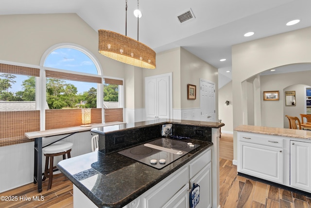 1710 Deerfield Ct SW Unit 4A, Ocean Isle Beach, NC 28469 - kitchen with arched walkways, black electric stovetop, light wood-style floors, lofted ceiling, and white cabinetry