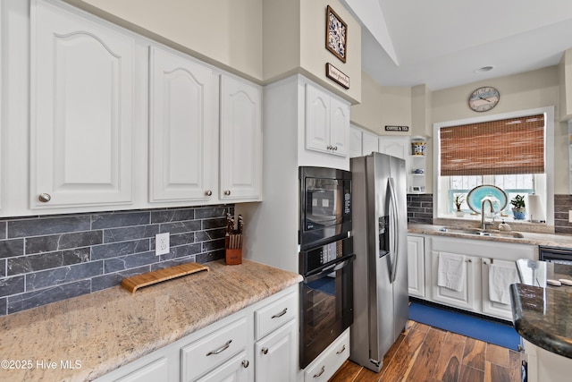 1710 Deerfield Ct SW Unit 4A, Ocean Isle Beach, NC 28469 - kitchen featuring black appliances, a sink, white cabinets, backsplash, and light stone counters
