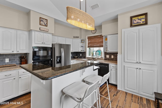 1710 Deerfield Ct SW Unit 4A, Ocean Isle Beach, NC 28469 - kitchen featuring black appliances, white cabinets, a breakfast bar, and dark stone counters