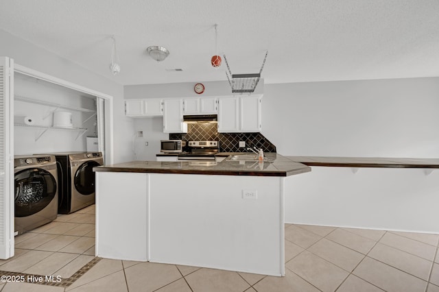 2910 Mulberry Ln Unit B, Greenville, NC 27858 - kitchen featuring appliances with stainless steel finishes, separate washer and dryer, under cabinet range hood, dark countertops, and white cabinetry