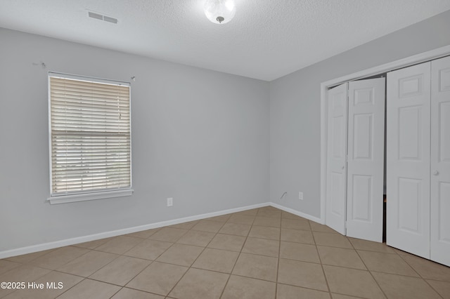 2910 Mulberry Ln Unit B, Greenville, NC 27858 - unfurnished bedroom with a textured ceiling, a closet, and light tile patterned floors