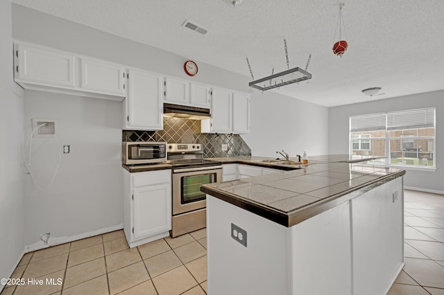 2910 Mulberry Ln Unit B, Greenville, NC 27858 - kitchen with stainless steel appliances, a peninsula, white cabinets, backsplash, and light tile patterned floors