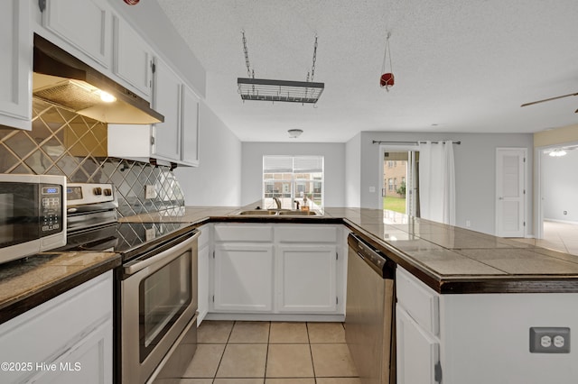 2910 Mulberry Ln Unit B, Greenville, NC 27858 - kitchen with appliances with stainless steel finishes, a peninsula, decorative backsplash, under cabinet range hood, and light tile patterned floors