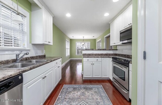 kitchen featuring dark wood-style flooring, white cabinetry, a chandelier, a sink, and stainless steel appliances
