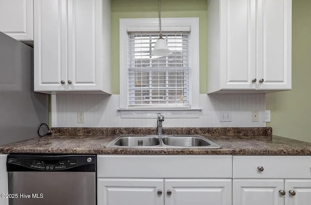 kitchen with pendant lighting, dark countertops, dishwasher, a sink, and white cabinets