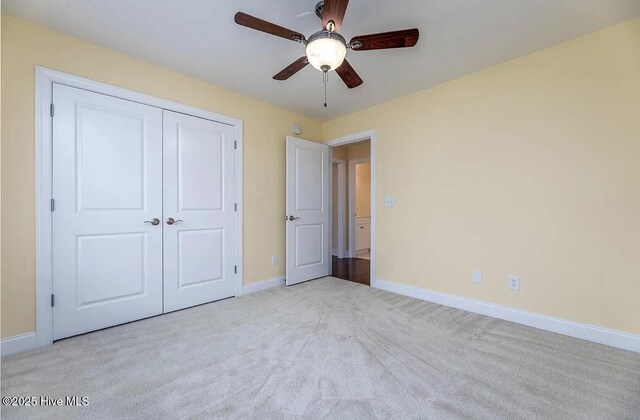 unfurnished bedroom featuring baseboards, light carpet, ceiling fan, and a closet