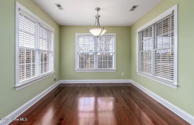 unfurnished dining area with baseboards, dark wood-style floors, and visible vents