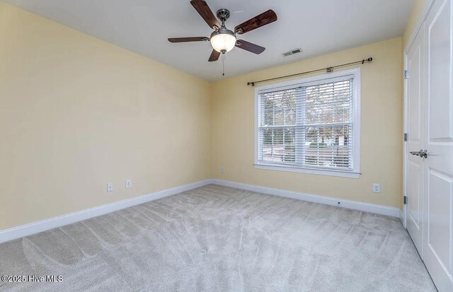 empty room with visible vents, a ceiling fan, baseboards, and light colored carpet
