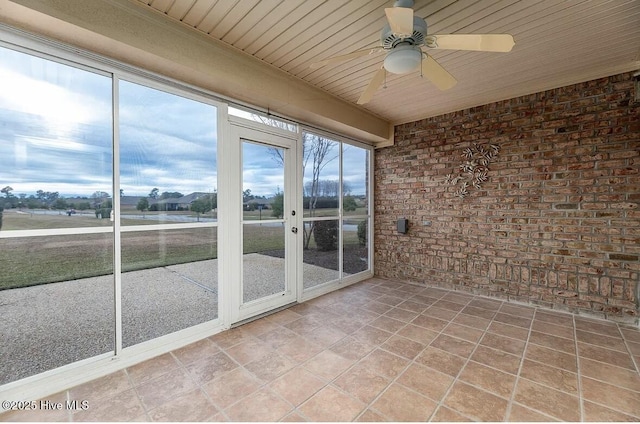 unfurnished sunroom with a ceiling fan, wood ceiling, and brick wall