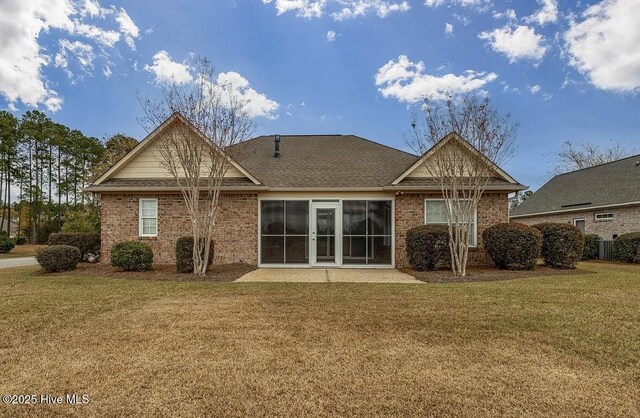 back of property featuring roof with shingles, a yard, and brick siding