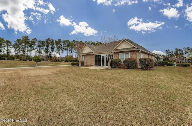 back of property with brick siding, a yard, and a patio