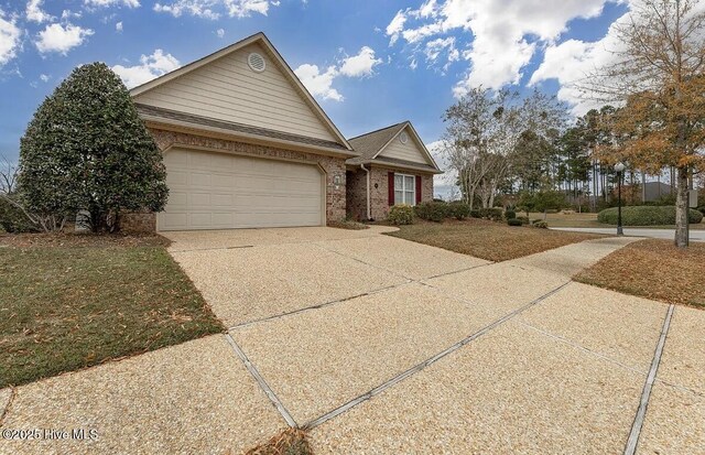 single story home with brick siding, a garage, and driveway