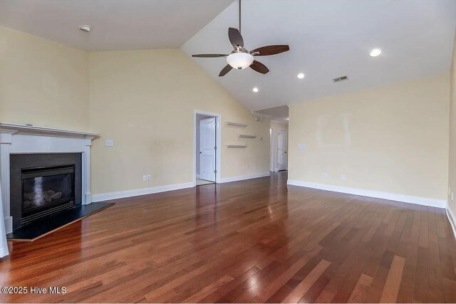 unfurnished living room with a ceiling fan, visible vents, wood finished floors, high vaulted ceiling, and a glass covered fireplace