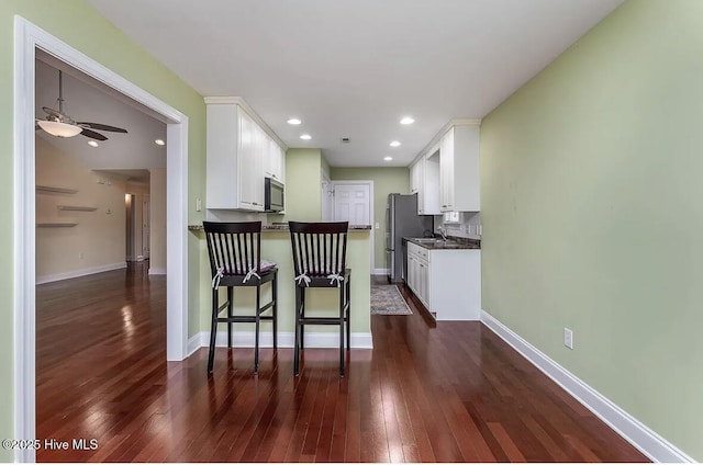 kitchen with dark countertops, freestanding refrigerator, dark wood finished floors, and white cabinetry