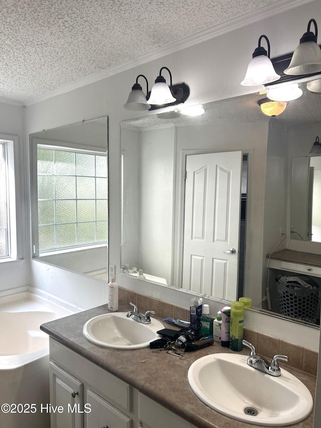 bathroom featuring a sink, a bath, ornamental molding, and a textured ceiling