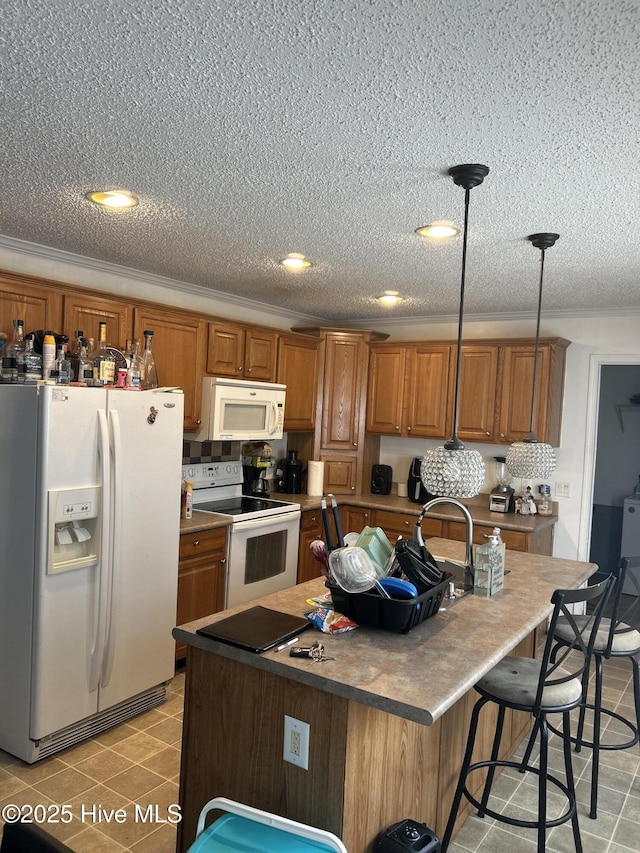 kitchen with brown cabinets, white appliances, a kitchen island with sink, decorative light fixtures, and light tile patterned floors