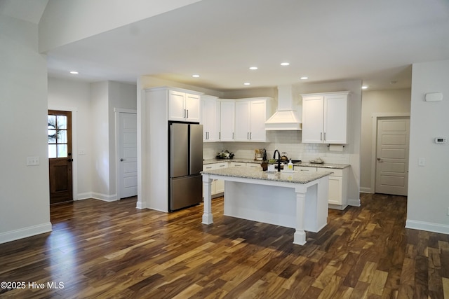 kitchen with freestanding refrigerator, dark wood-style floors, premium range hood, and tasteful backsplash