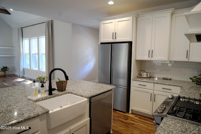 kitchen with a sink, stainless steel appliances, wood finished floors, and white cabinetry