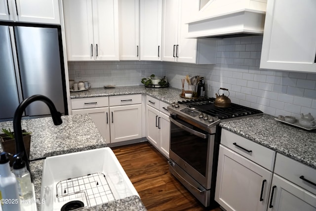 kitchen featuring premium range hood, white cabinets, backsplash, and stainless steel appliances