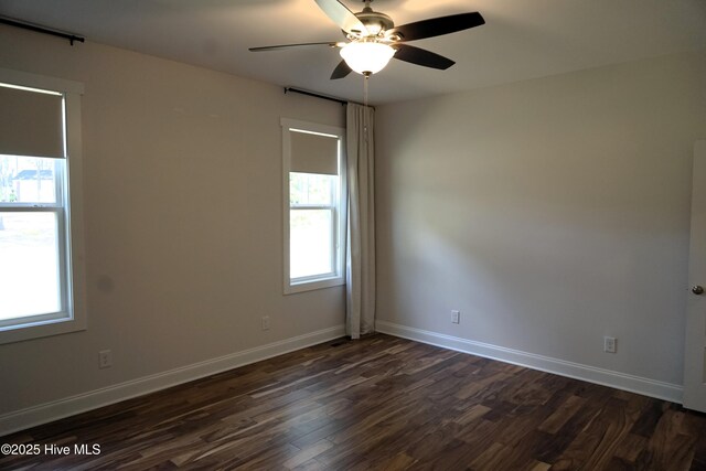 spare room featuring baseboards, dark wood-style flooring, and ceiling fan