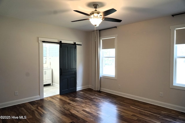 interior space with a wealth of natural light, a barn door, and dark wood-type flooring