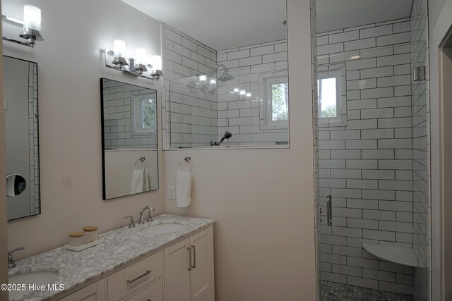 bathroom featuring a sink, a stall shower, double vanity, and a healthy amount of sunlight