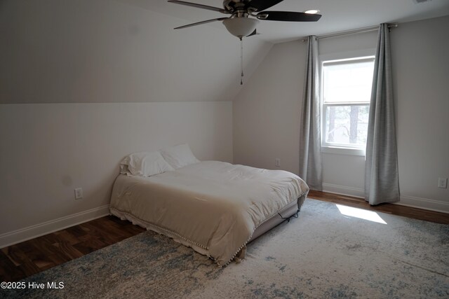 bedroom with baseboards, wood finished floors, and lofted ceiling
