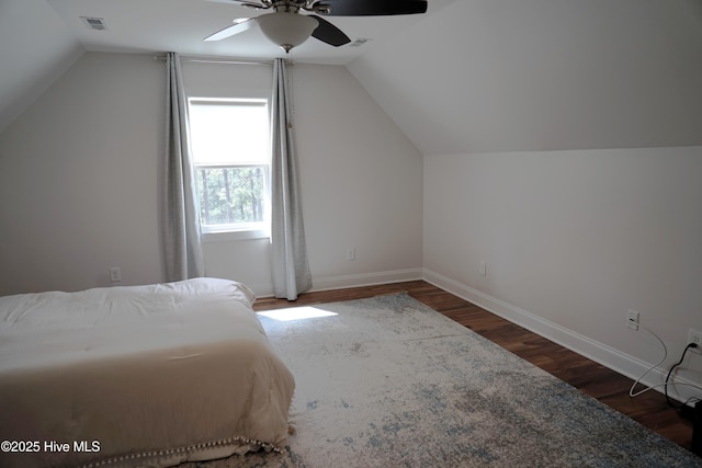 bedroom featuring baseboards, vaulted ceiling, wood finished floors, and visible vents