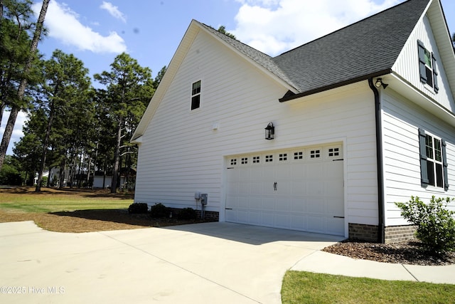 view of side of home with roof with shingles and driveway